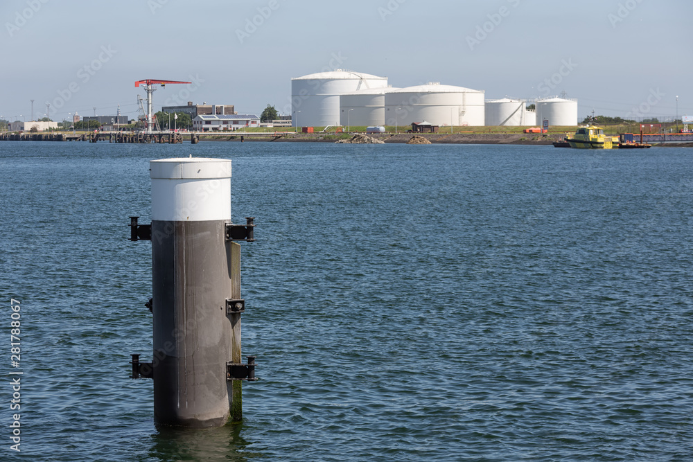 Wall mural dutch harbor vlissingen with steel bollard and fuel storage tanks