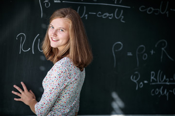 Pretty, young female student/teacher in front of a blackboard during math class