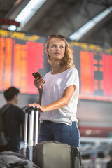 Young woman with her luggage at an international airport, before going through the check-in and the security check before her flight