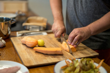 Obraz na płótnie Canvas Mann schneidet mit großem Küchenmesser eine Süsskartoffel in Streifen, Nahaufnahme Hand