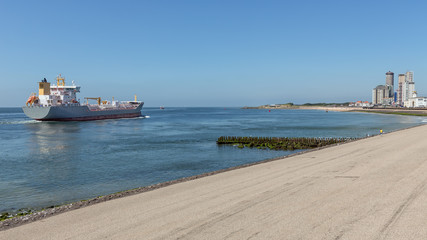 Dutch waterside Vlissingen with cargo ship sailing close to coast