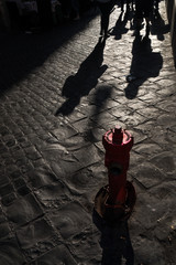 Shadows of people on the road and red hydrant