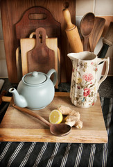  Tea pot on wooden board with lemon and ginger. Wooden boards in the background.