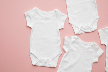 Cute baby white body suit layout on a pastel pink background