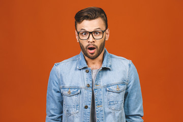 Stupefied attractive young bearded man looks with astonishment into camera, being amazed with...