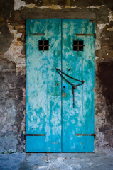 Dettaglio di una vecchia porta di legno dipinta d'azzurro con una catena che la tiene chiusa in una calle di Venezia