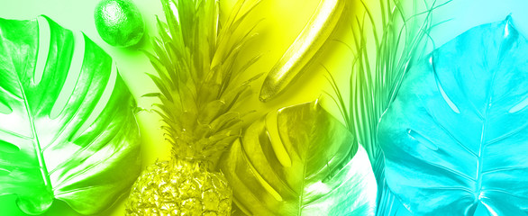 Creative layout. Gold pineapple and golden palm, monstera on rainbow gradient background with copy space. Top view. Tropical flat lay. Exotic food concept in trendy neon colors. Banner