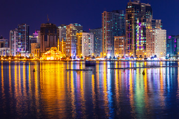 Sharjah skyline with skyscrappers and mosque at night, United Arab Emirates
