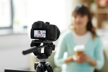 blogging, technology, videoblog and people concept - camera recording video blog of nice asian woman or blogger with takeaway coffee cup at home