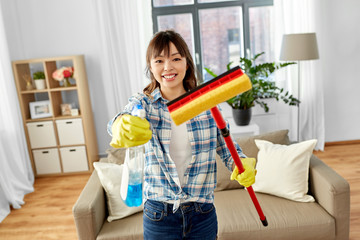 cleaning, housework and housekeeping concept - happy asian woman or housewife in gloves with window cleaner and sponge mop at home