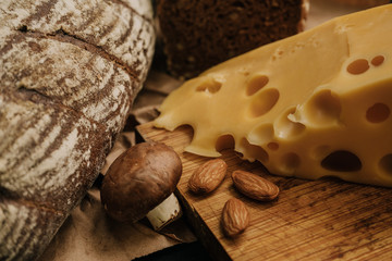 Fresh bread and cheese on paper on wooden black background