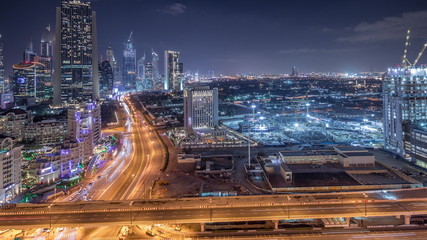 Construction activity in Dubai downtown with cranes and workers night timelapse, UAE.