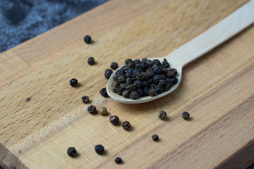 Black pepper on wooden spoon.
