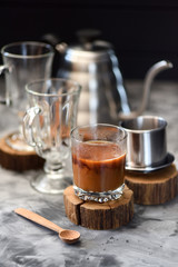 Milk coffee Vietnamese style prepared in drip coffee maker phin on dark background