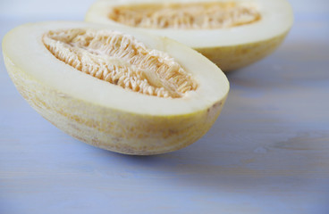 organic ripe yellow sweet melon cut in half with seed isolated on a white blue background. Healthy food.