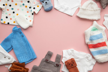 Cute baby clothes layout on a pastel pink background