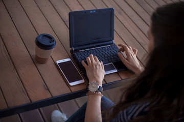 Neat young female hands with a modest manicure, with large wrist watches, work at a laptop,...