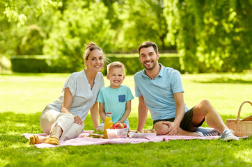 family, leisure and people concept - portrait of happy mother, father and little son having picnic at summer park
