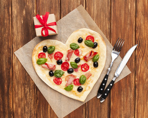 Flat lay heart shaped pizza with tableware