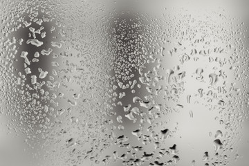Closeup macro photo of water drops captured on glass window with dark background overlooking city street.