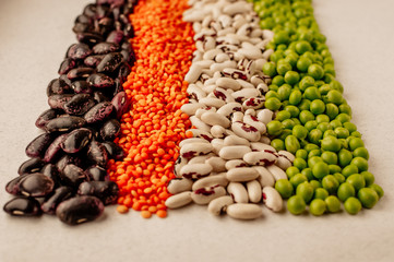 Collection set of various dried legumes laid out in a horizontal line: red lentils,green peas, red beans, white beans close-up on a white background. Selective focus