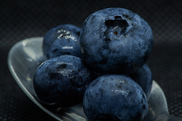 Blueberries Macro closeup photo of superimposed on top of each other and tiled in a teaspoon against a dark background.