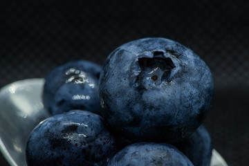 Blueberries Macro closeup photo of superimposed on top of each other and tiled in a teaspoon against a dark background.