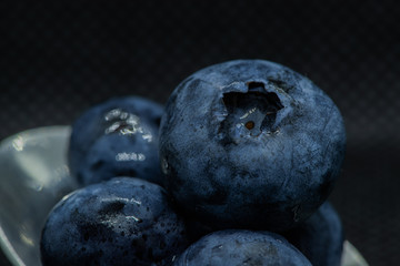 Blueberries Macro closeup photo of superimposed on top of each other and tiled in a teaspoon against a dark background.