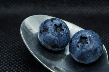 Blueberries Macro closeup photo of superimposed on top of each other and tiled in a teaspoon against a dark background.