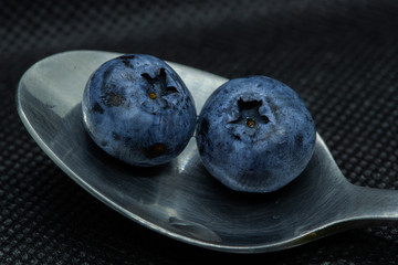 Blueberries Macro closeup photo of superimposed on top of each other and tiled in a teaspoon against a dark background.