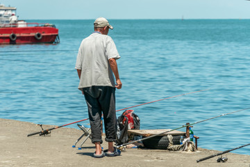 A man fisherman with fishing rods on the harbor of the Black Sea on a sunny day