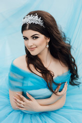 Beautiful girl with long brown curly hair. Closeup portrait with a pretty face of the young girl. Amazing luxury woman in stylish dress.