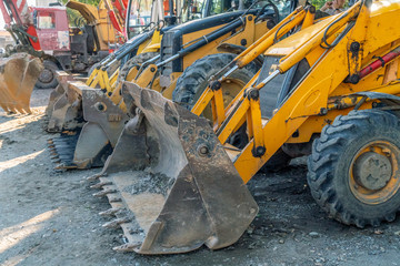 Several close-up bulldozer buckets in a row in sunny weather