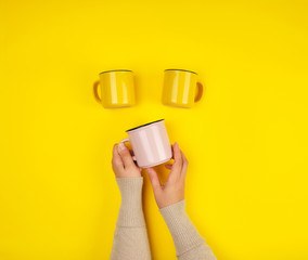 ceramic cups and female hands on a yellow background