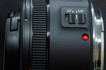 Obraz premium Macro closeup photo of lens to dslr camera on dark background view of red dot and silver extension ring and autofocus button.