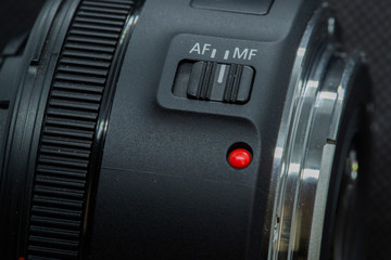 Macro closeup photo of lens to dslr camera on dark background view of red dot and silver extension...