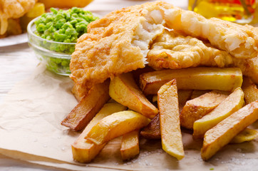 Traditional British street food fish and chips with mushy peas on parchment paper