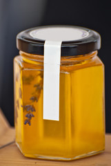 Jar of natural honey on a wooden stand. Homemade honey with sprigs of lavender.