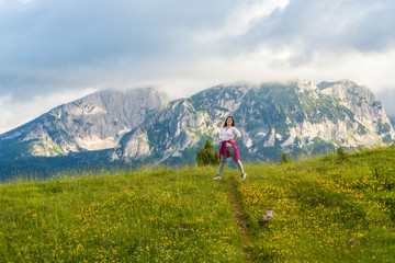 Fototapeta na wymiar happy European girl stands on background of Montenegro mountains in Durmitor park, with copy space