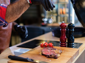 Chef salts stealk before grilling in a restaurant