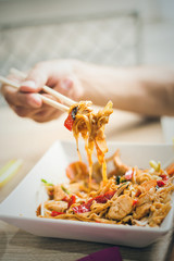 man hand with chopsticks eat thai food closeup selective focus