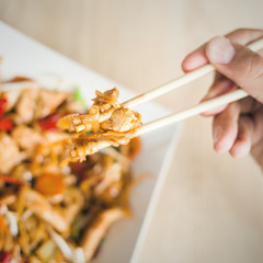 man hand with chopsticks eat thai food closeup selective focus