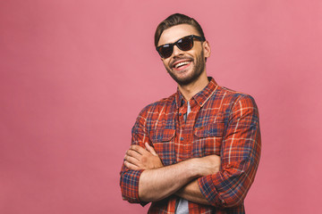 Portrait of a handsome happy cool young man in sunglasses enjoying over pink background.