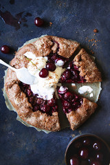 Chocolate crostata with cherry and ice-cream on dark blue background.