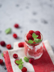 Raspberry cold summer cream dessert parfait on a grey table with mint