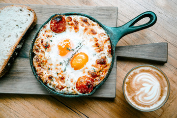 Top view coffee latte and egg pan Shakshuka on wooden table