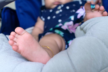 Newborn feet. New born is dressing blue dress. Baby is wearing Ankle bracelet. Infant is 3 months. - Kid, Children and person body path.