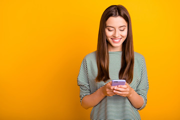 Photo of excited cheerful girlfriend browsing through her favorite page of some social media while isolated with yellow background