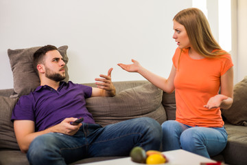 Angry wife and husband are having conflict because husband is watching tv too much.