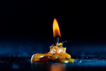 The flame of a burning candle against a dark background.